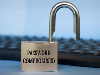 Password compromised text engraved on padlock with blurred keyboard background. Password security...