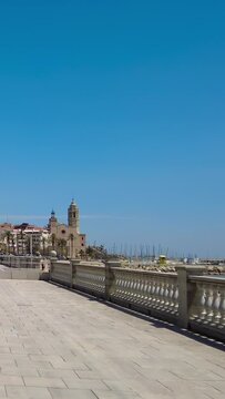 Promenade with the church of San Bartomeu i Santa tecla in the background, in the mediterranean town of Sitges, Province of Barcelona.