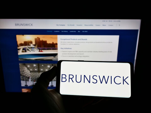 Stuttgart, Germany - 12-12-2021: Person holding smartphone with logo of American company Brunswick Corporation on screen in front of website. Focus on phone display.