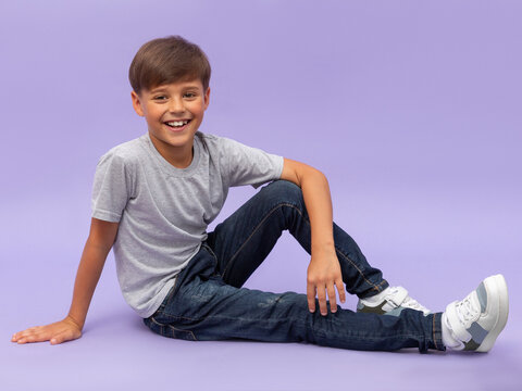 Portrait of young boy sitting isolated over a lilac background