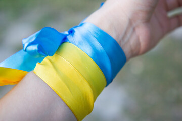 blue-yellow ribbons on the hands, the flag and the trident of Ukraine