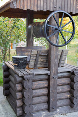 rural wooden well and black bucket of water