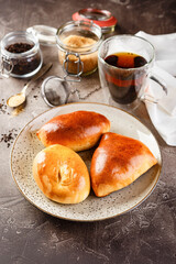 Sweet yeast dough pies with different fillings on platter and glass of tea