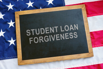 Fototapeta premium Student loan forgiveness concept. USA flag and blackboard on it.