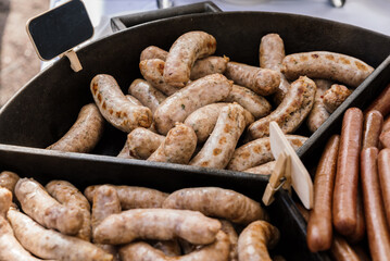 three different types of grilled sausages in a frying pan. pork and other types of hot delicious grilled sausages