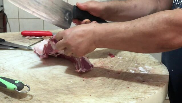 Butcher cuts meat. Hands of man cutting lamb chops.