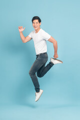 Nice asian guy in white t-shirt and jeans jumping isolated on blue background