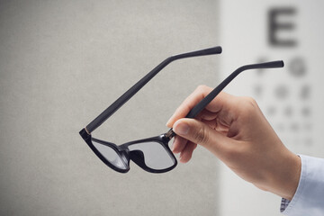 Optometrist holding glasses and eye chart