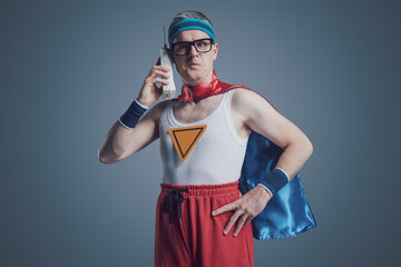 Funny superhero making a phone call using a cordless telephone © stokkete