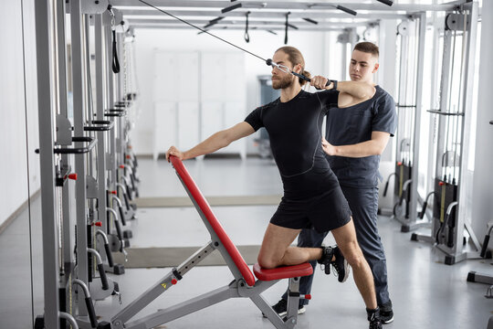 Man doing exercises on decompression simulators with the help of rehabilitation specialist. Concept of physical therapy for health and recovery. Idea of kinesiology in the treatment of back