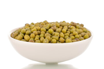Plenty of organic uncooked mung beans in a white ceramic saucer, close-up, isolated on a white background.