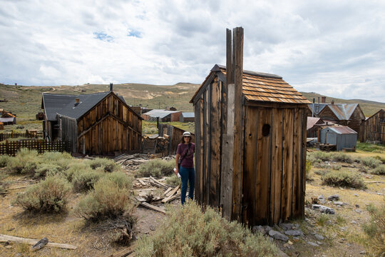 The famous Bodie Ghost Town Looking at a Beautiful Mature Woman looking at an Outhouse
