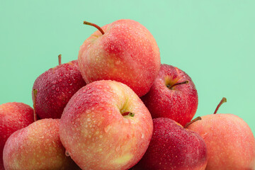 Red apples with water drops, macro. Ripe red apples on a green background. Heap of red delicious apples. Shallow depth of field.