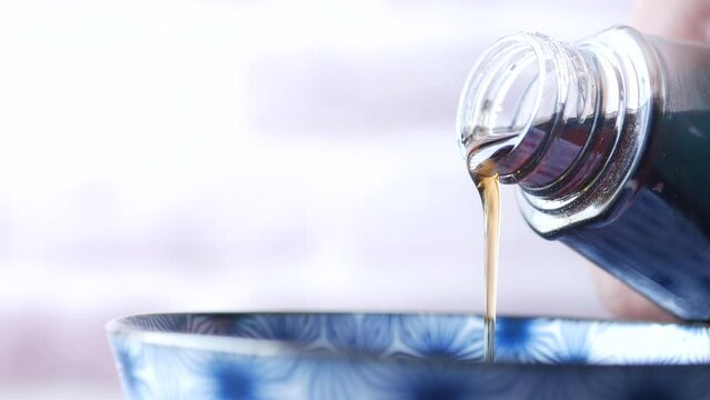 Bottle of maple syrup pouring close up 