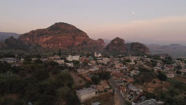 Aerial slow movement around Tlaycapan surrounded by buildings and mountains during sunset