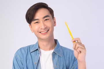Young smiling man holding toothbrush over white background studio, dental healthcare and Orthodontic concept..