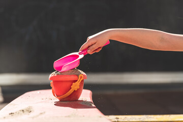 a girl makes a tower of sand from a bucket