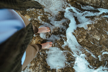 overhead view man barefoot walking by sea rocky beach