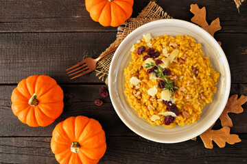 Fall pumpkin risotto with cranberries and parmesan cheese. Overhead view table scene on a rustic...