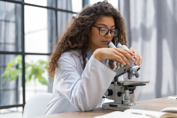 Fototapeta premium Female scientist in medicine coat works in a scientific laboratory