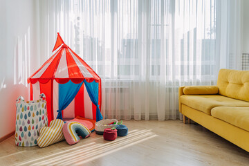 Children's room with a play tent, pillows and toys in baskets. Nursery Storage Ideas.