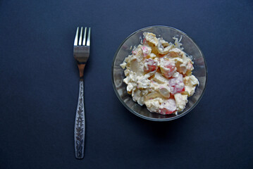 Delicious salad of vegetables and sauces in a salad bowl with a fork. Salad on a black background.