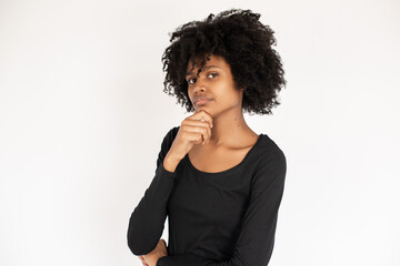 Fototapeta na wymiar Portrait of pensive African American woman with hand on chin. Young female model wearing black dress looking at camera and thinking. Doubt and uncertainty concept