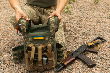 A military man in a military body armor with a tactical Kalashnikov automatic machine gun in his hands. Body armor with combat butts and ammunition. Ukrainian army. Military concept. No war.