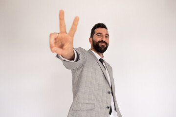 Portrait of friendly man with beard. Male in suit gesturing, showing victory sign. Portrait, emotion concept