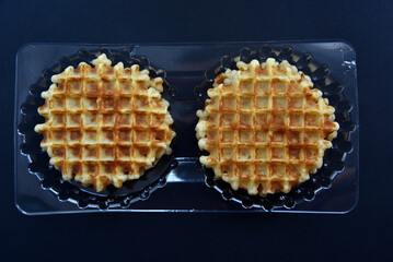 Viennese waffles in plastic packaging on a black background. Delicious waffles as breakfast.