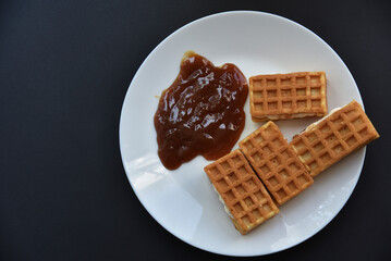 Delicious Viennese waffles with jam on a white plate. A sweet breakfast of Viennese waffles.
