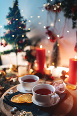 Obraz na płótnie Canvas two cups of black or berry red hot english christmas tea with decor and candle