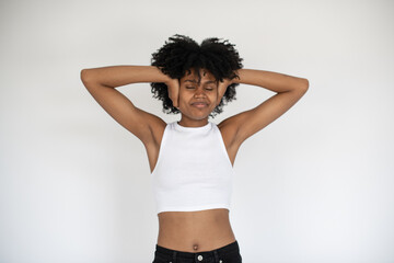 Fototapeta na wymiar Portrait of carefree African American woman with hands at head. Young girl wearing white crop top and jeans standing against white background. Happiness concept