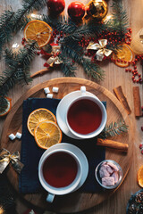 Obraz na płótnie Canvas two cups of black or berry red christmas tea, decorated candle, top view flatlay