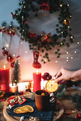 mulled red wine gluhwine in cup with orange, christmas decor table with candles