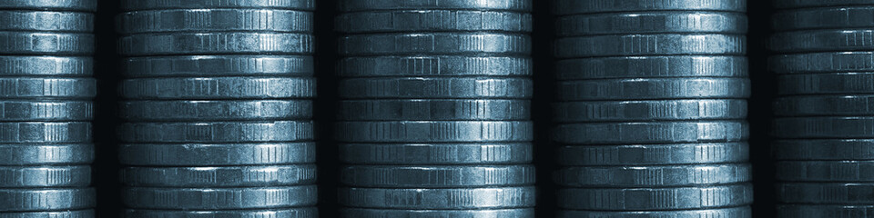 Obraz premium Stack of coins close-up. Coin texture. Blue tinted business banner made of many coin edge. Economy finance and bank header. Abstract money wall. Tax, credit and currency change. Macro