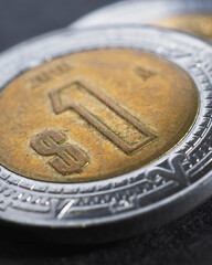 Coin of 1 one Mexican peso close-up. Peso of Mexico. News about economy or currency. Loan and credit. Money and taxes. Focus on peso sign. Vertical stories. Macro