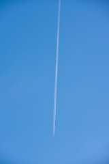 The contrail of an airplane in the blue sky. The flight of a passenger plane.