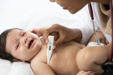 doctor measuring baby's temperature and baby crying on bedroom