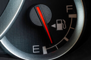 Low fuel gauge on car dashboard, close-up.