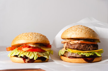 Natural photo of two juicy burgers in white paper packaging.