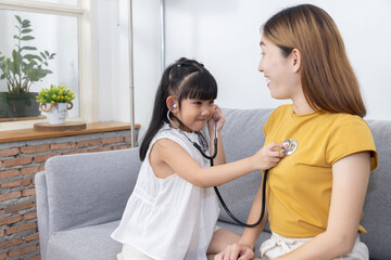 Asian Girl Hold Stethoscope Imagines Herself to be a Doctor Listen to Her Mom Heart Pulse