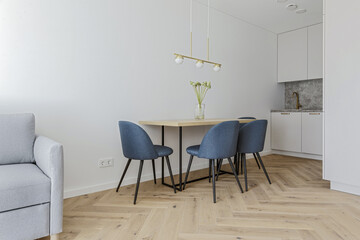Modern minimalist kitchen and dining room interior design  with wooden furniture, oak floor. blue chairs.  Aesthetic simple interior design concept.