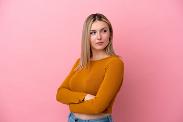 Young caucasian woman isolated on pink background keeping the arms crossed