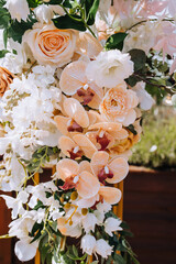 A beautiful arch decorated with fresh multi-colored flowers stands in the park at the wedding ceremony. Photography, decoration element.