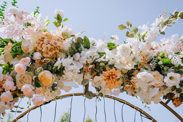 A beautiful arch decorated with fresh flowers stands in the park at the wedding ceremony....