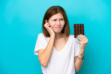 Young English woman with chocolat isolated on blue background frustrated and covering ears
