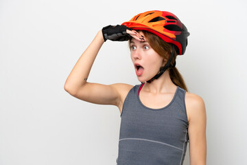Young cyclist English woman isolated on white background doing surprise gesture while looking to the side