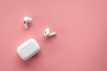 Fototapeta Wireless in-ear headphones with a case on a pink background, flat lay. obraz