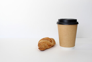 Craft coffee cup with croissant on white background. French breakfast. Flat lay, top view.